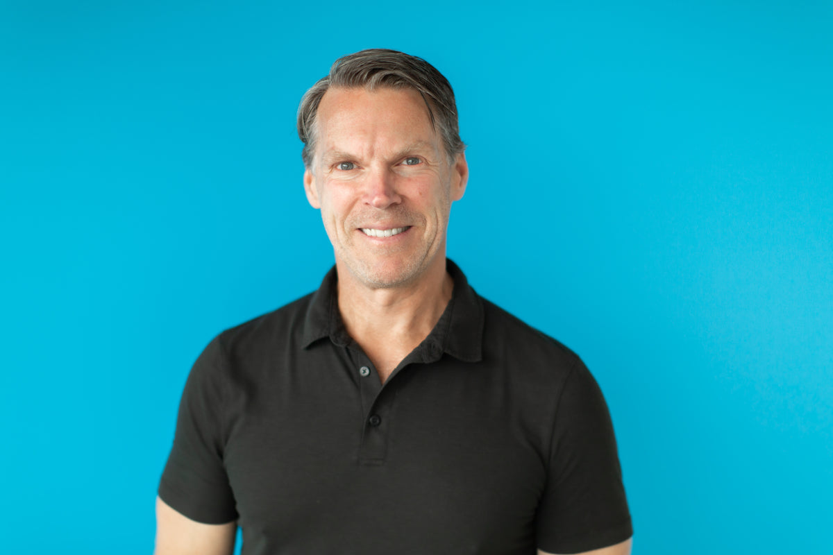 Dr. Darren Burke wearing a black polo shirt against a blue background